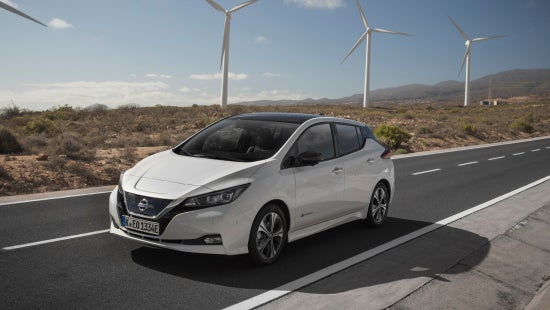 Nissan vehicle driving on road, wind turbines in the background | Casa Nissan in El PASO TX